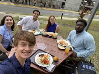A group of students eating lunch together at a picnic table at the University of Costa Rica campus