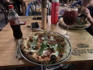 Two pizzas, a bottle of coke, and a glass of sangria on a wooden table